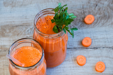 Fresh carrot juice in bottles on a grey wooden table
