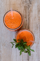 Fresh carrot juice in bottles on a grey wooden table