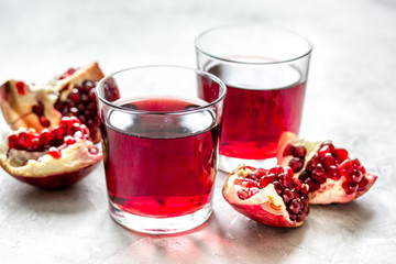 glass of pomegranate juice with fresh slices on stone background