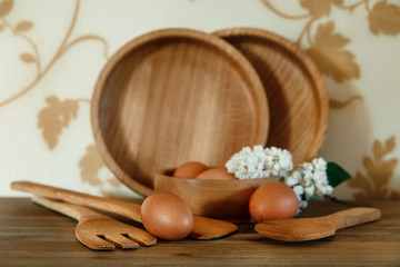 Wooden Plates,Kitchen Equipment.Eggs,White Branch of Lilac.Wooden Table.Floral Background.Selective Focus