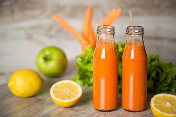 Fresh carrot juice in bottles on a grey wooden table