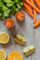 Fresh carrot juice in bottles on a grey wooden table