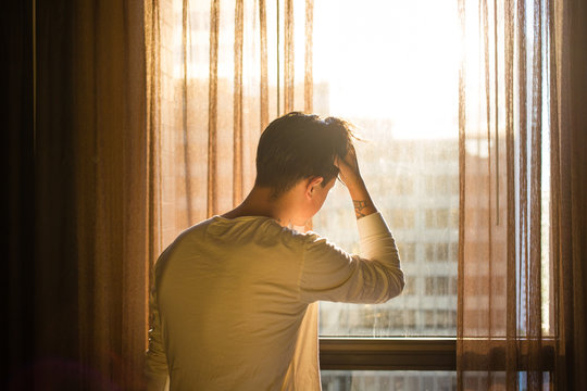 Man in sunlight looking out of window