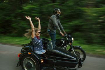 Blurred motion image of couple riding motorbike with sidecare