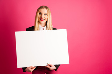 Young business woman holds blank banner isolated over pink background