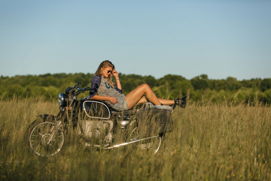 Woman in field sitting motorbike