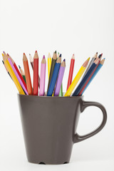 colored pencils in mug on white background