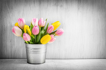 Fresh bouquet of tulips in a metal pot on rustic wood.