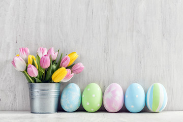 Easter eggs and a spring bouquet of tulips on a wooden table.