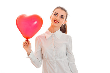 young cute brunette woman in stylish white t-shirt with red heart in her hands looking away and smiling isolated on white background