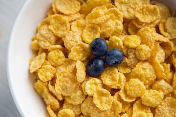 granola with blueberries in white bowl on wooden white background