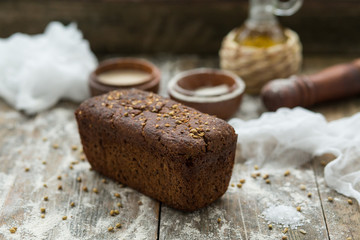 Close up view of fresh brown crispy loaf of bread lying on the wooden table sprinkled with flour.