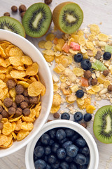 granola with blueberries in white bowl on wooden white background