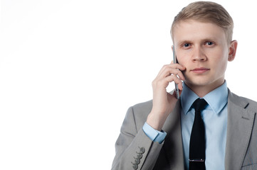 young businessman talking on the phone and looks at you. in a business suit on a white background.