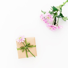Craft gift box and flowers on white background. Flat lay, top view. Floral background.