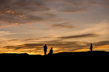 silhouette of three people over rocks
