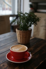 A large red coffee mug on a wooden table.
