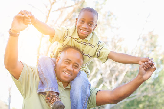 Happy African American Father and Son Riding Piggyback Outdoors At The Park.