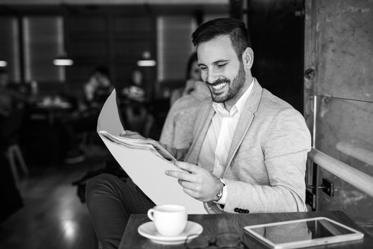 Young businessman reading newspapers during coffee break