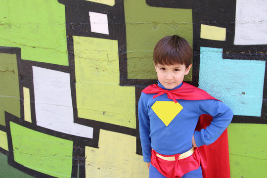 little kid with a superhero costume in a green wall