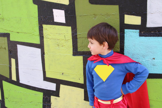 child with a superhero costume in a green wall