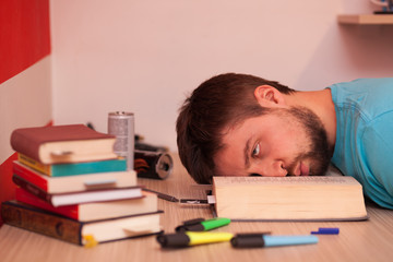 Comatose student with his head lying in the middle of a book while studying