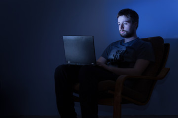 Man working on a laptop in a dark room at night