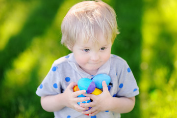 Little boy hunting for easter egg in spring garden on Easter day