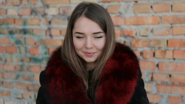 Portrait of a cute girl on the brick wall background.Full hd video
