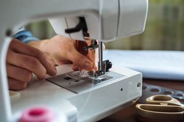 Fototapeta na wymiar Woman working on sewing machine. Close up view