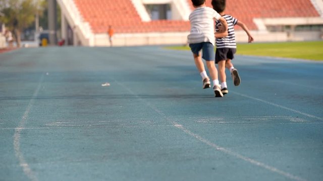 Young Asian boy running on blue track,