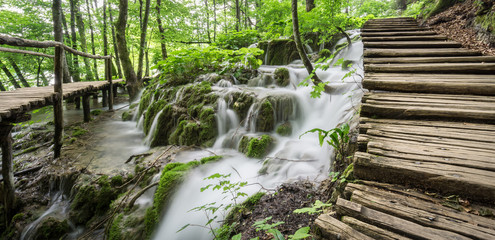 A wooden pathway meanders over waterfalls and through the forest at Plitvice Lakes National Park in Croatia.