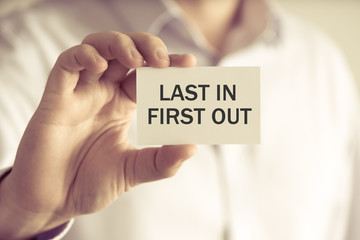 Businessman holding LAST IN FIRST OUT message card