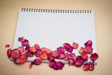 Black notepad. Realistic template notebook. Blank cover design. with dried rose petals and leaf. on cardboard background.
