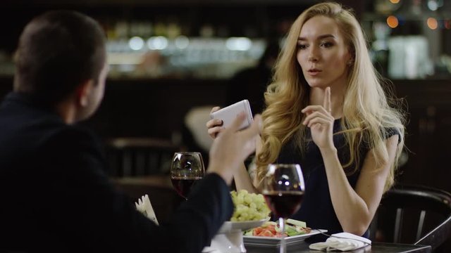 cute girl taking a selfie in a pompous cafe and make her man waiting
