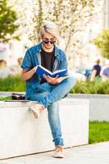 Hipster guy holding notebook sitting on ledge