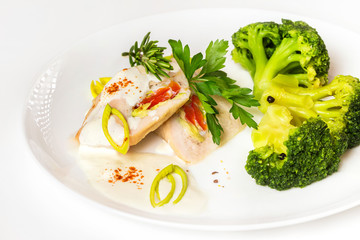 Plate of steamed chicken and broccoli with white sauce isolated.