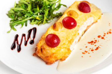 Fresh fish baked with cheese and grapes and decorated wit greens isolated at white background.