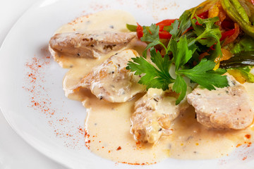 Plate of braised chicken meat with white sauce isolated.