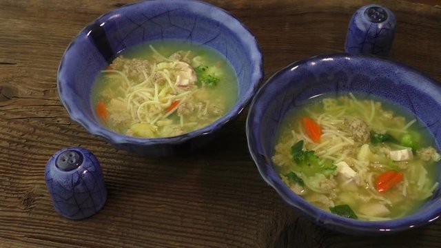 Clear soup with chicken and noodles. Broth with carrots, onions various fresh vegetables in a bowl
