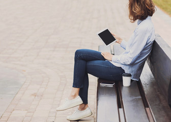 Obraz premium Young girl using digital tablet in a park. Online shopping and business concept