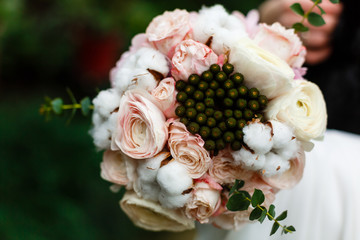 Beautiful winter wedding bouquet with cones, cotton and spruce branches. Bride holding a bridal bouquet.