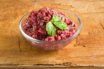 Minced meat in the bowl on the wooden table in the kitchen. Healthy eating and lifestyle.