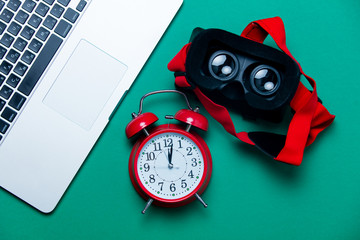 beautiful alarm clock, pink shopping bag, biloculars and modern silver laptop on the wonderful blue background