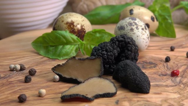 black truffles, quail eggs and basil on a wooden board