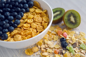 granola with blueberries in white bowl on wooden white background