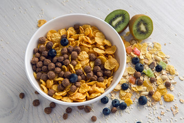 granola with blueberries in white bowl on wooden white background