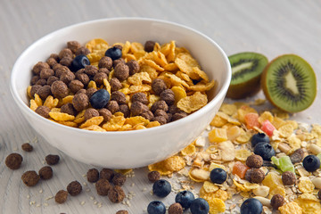 granola with blueberries in white bowl on wooden white background