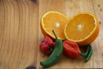 red & green chilli with orange  sliced open on a wooden cutting board
