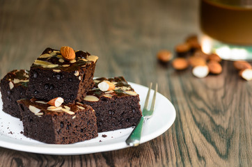 Almond Dark Brownies with Coffee in white plate on wood table background.